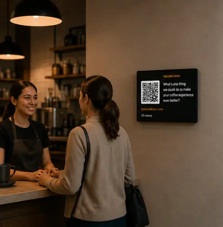 A customer at a coffee shop counter facing a wall-mounted screen that reads “The one voice: what is one thing we could do to make your coffee experience even better?” with a QR code and a voice count.