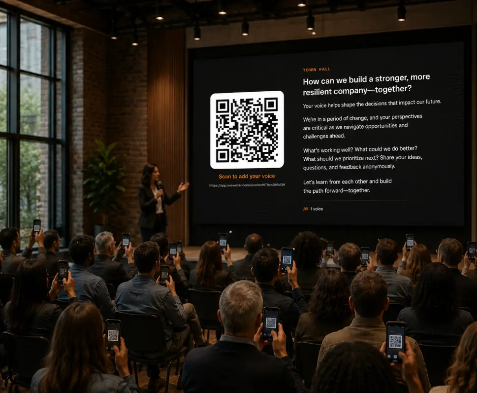An all-hands audience holding up phones to scan a One Voicer QR code, with the blended answer on the screen at the front of the room.